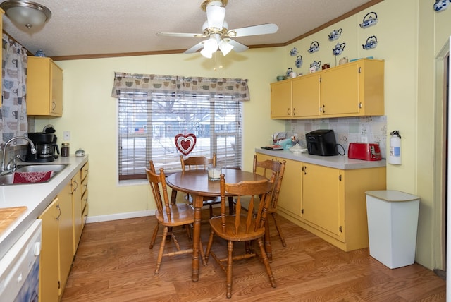 kitchen featuring vaulted ceiling, ornamental molding, sink, and light hardwood / wood-style flooring