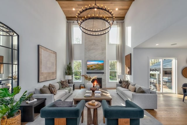 living room featuring an inviting chandelier, wood ceiling, a healthy amount of sunlight, and a high ceiling