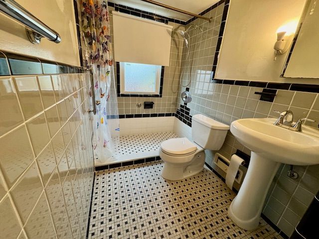 bathroom with toilet, a baseboard heating unit, tile walls, and a shower with curtain