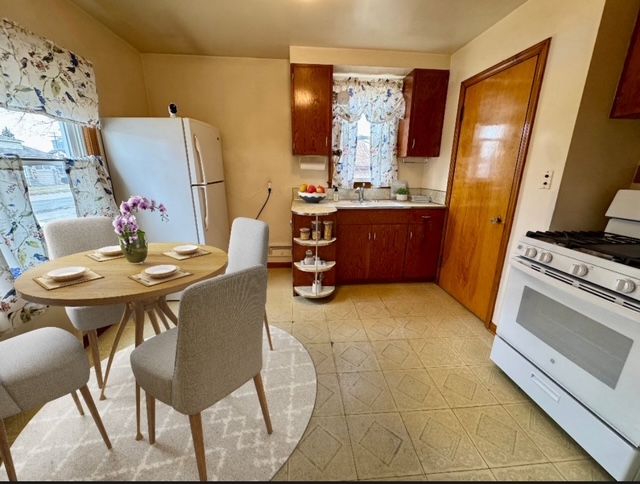 kitchen featuring white appliances, a baseboard radiator, and sink