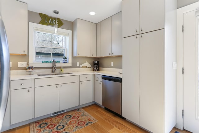 kitchen featuring sink, white cabinets, hanging light fixtures, and dishwasher