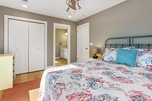 bedroom featuring connected bathroom, light hardwood / wood-style flooring, ceiling fan, and a closet