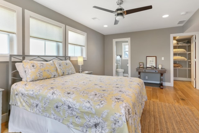 bedroom featuring ensuite bath, ceiling fan, multiple windows, a walk in closet, and a closet