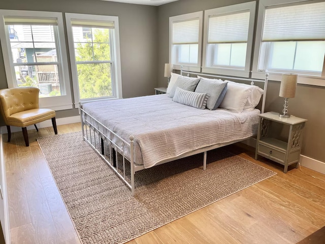 bedroom with multiple windows and light wood-type flooring