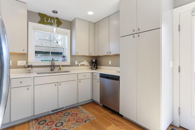 kitchen with sink, decorative light fixtures, light wood-type flooring, stainless steel appliances, and white cabinets