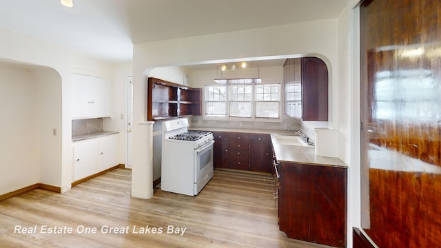 kitchen featuring white gas range, sink, and light wood-type flooring