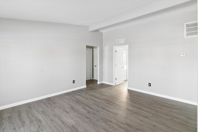 spare room with dark hardwood / wood-style flooring and lofted ceiling with beams