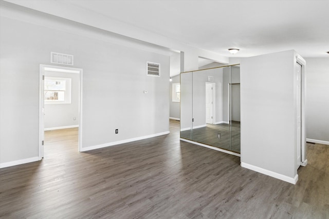 spare room with lofted ceiling and dark wood-type flooring