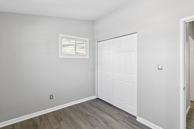 unfurnished bedroom with dark wood-type flooring and a closet