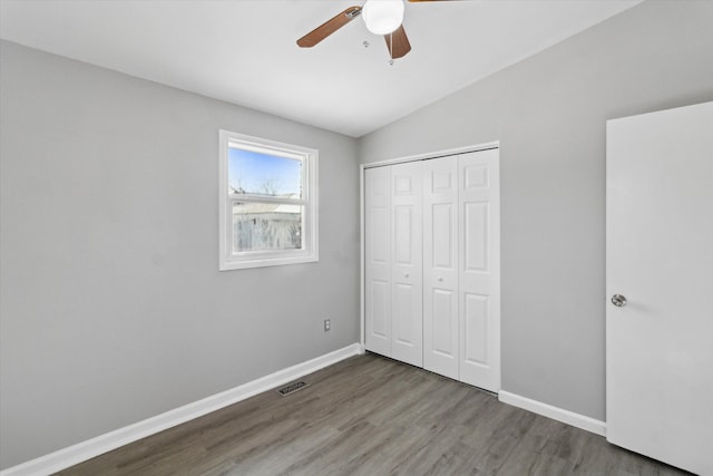 unfurnished bedroom featuring dark hardwood / wood-style flooring, vaulted ceiling, a closet, and ceiling fan