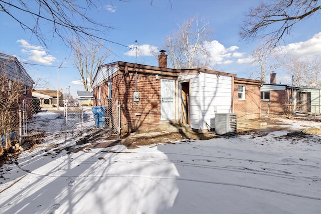 snow covered back of property featuring cooling unit