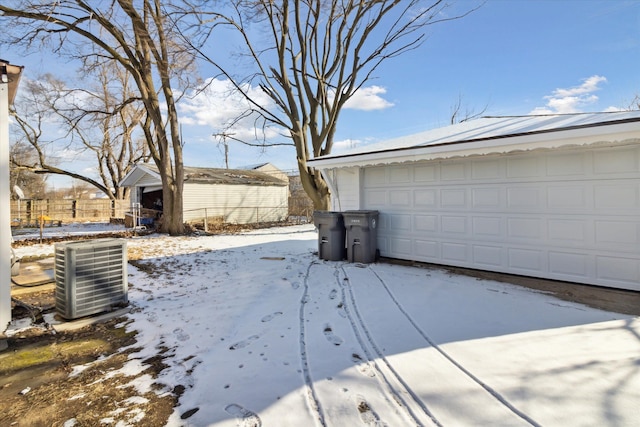 snowy yard featuring a garage, an outdoor structure, and cooling unit