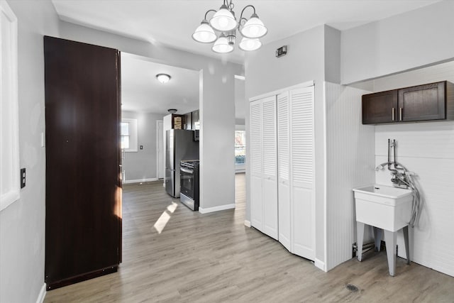 corridor featuring a wealth of natural light, a chandelier, and light wood-type flooring