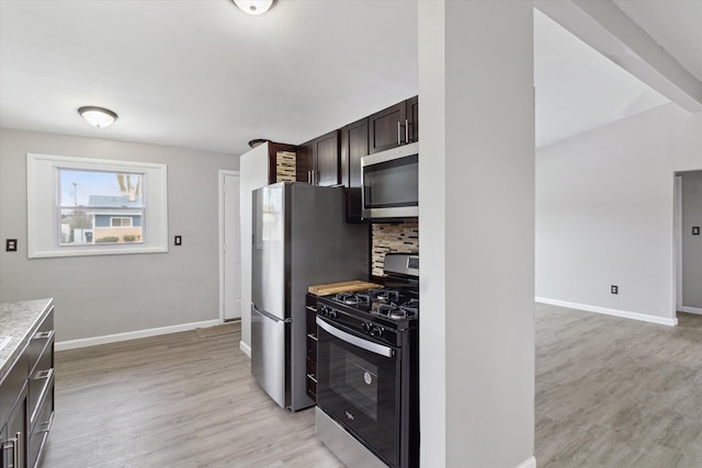 kitchen with appliances with stainless steel finishes, dark brown cabinets, backsplash, and light wood-type flooring