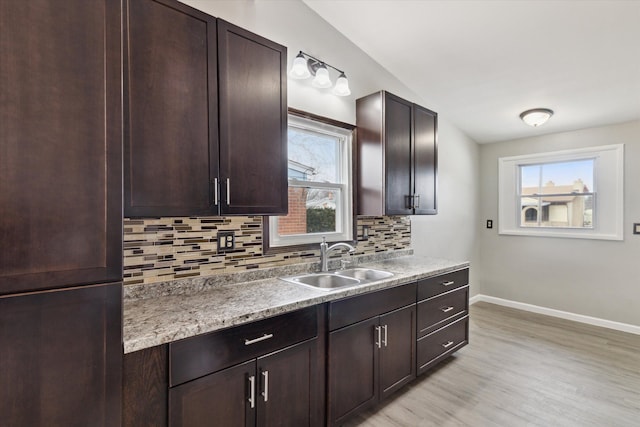 kitchen featuring dark brown cabinetry, sink, decorative backsplash, and light wood-type flooring