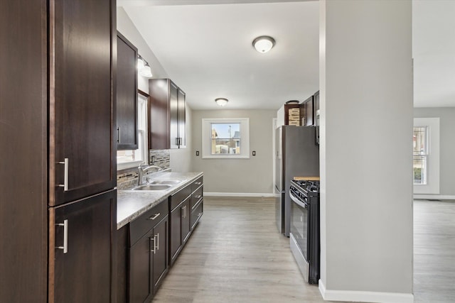 kitchen with sink, backsplash, dark brown cabinetry, light hardwood / wood-style floors, and gas range oven