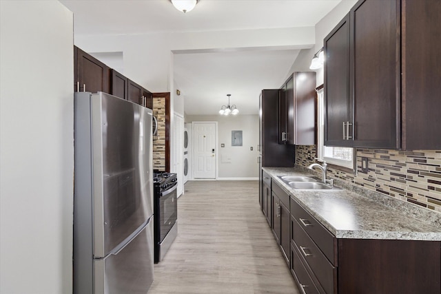 kitchen featuring appliances with stainless steel finishes, decorative light fixtures, sink, backsplash, and light hardwood / wood-style flooring