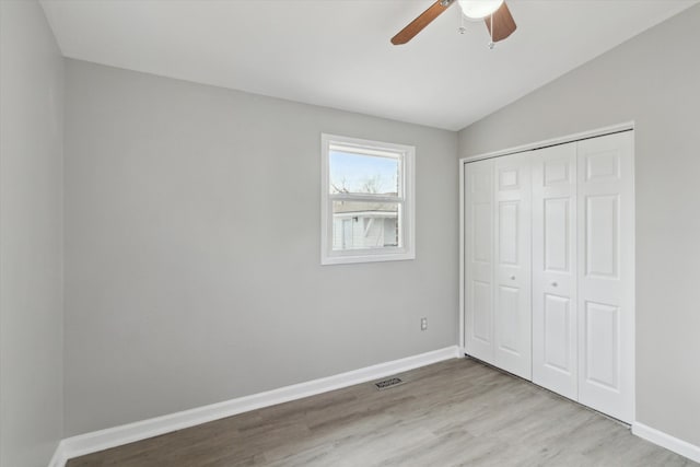 unfurnished bedroom featuring lofted ceiling, light hardwood / wood-style floors, a closet, and ceiling fan