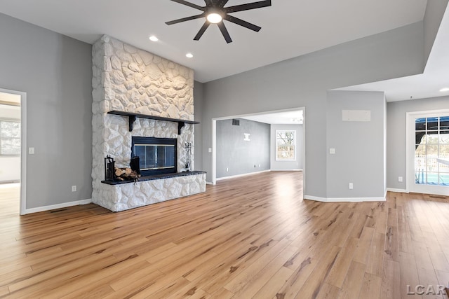 unfurnished living room featuring ceiling fan, a fireplace, and light hardwood / wood-style floors