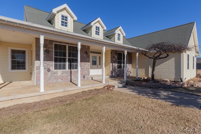 cape cod home featuring a porch and a front lawn