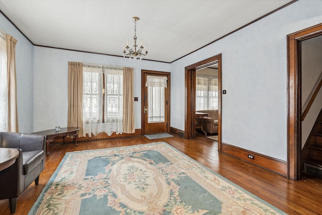 foyer entrance with crown molding, dark wood-type flooring, and a notable chandelier