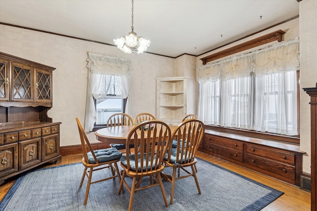 dining space with ornamental molding, a chandelier, and light wood-type flooring