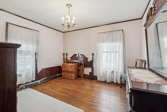 bedroom with hardwood / wood-style flooring, crown molding, and an inviting chandelier