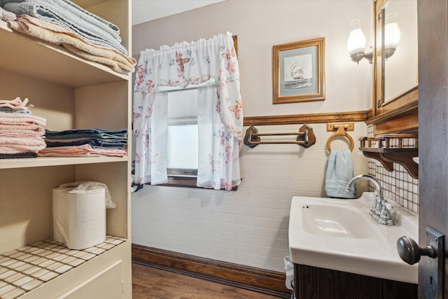 bathroom with wood-type flooring, vanity, and tile walls