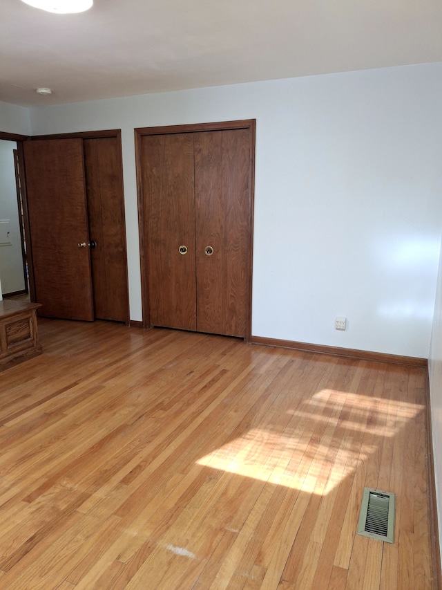 unfurnished bedroom featuring two closets and light hardwood / wood-style floors