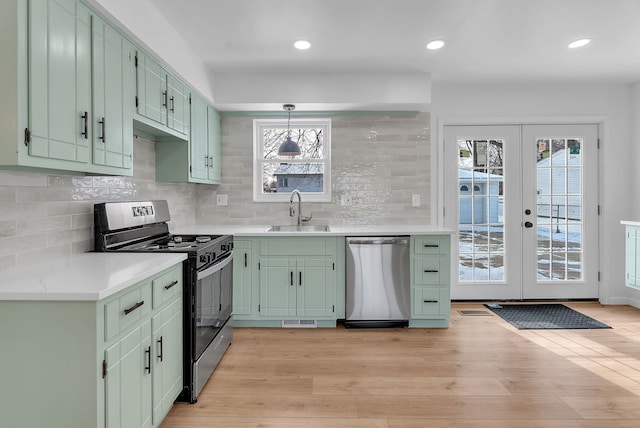 kitchen with green cabinets, appliances with stainless steel finishes, sink, and backsplash