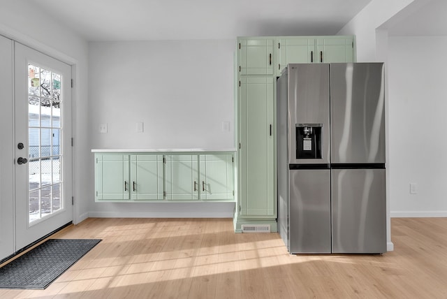 kitchen with green cabinets, stainless steel fridge with ice dispenser, and light wood-type flooring