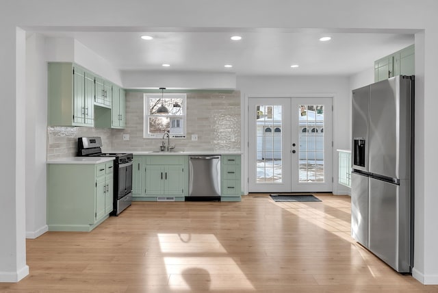 kitchen featuring sink, appliances with stainless steel finishes, tasteful backsplash, green cabinetry, and french doors