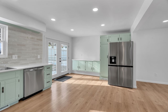 kitchen with stainless steel appliances, light hardwood / wood-style flooring, french doors, and green cabinetry