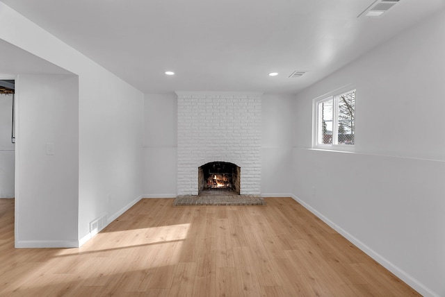 unfurnished living room featuring a brick fireplace and light hardwood / wood-style flooring