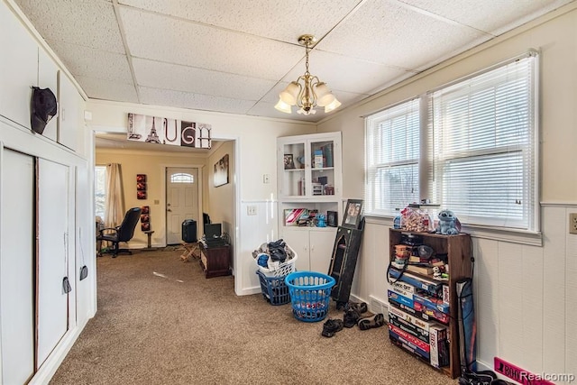 misc room with carpet floors, a paneled ceiling, and a chandelier