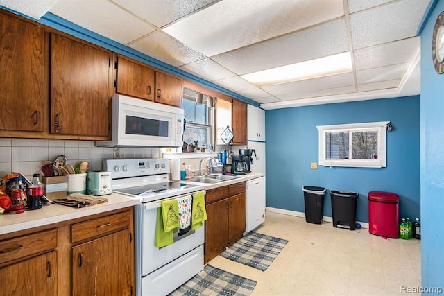 kitchen with sink, a drop ceiling, backsplash, and white appliances