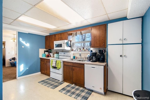 kitchen with white appliances, sink, decorative backsplash, and a drop ceiling