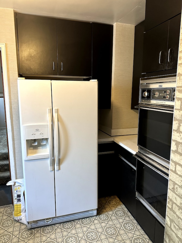 kitchen featuring white refrigerator with ice dispenser and black double oven