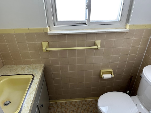 bathroom featuring vanity, toilet, tile patterned flooring, and tile walls