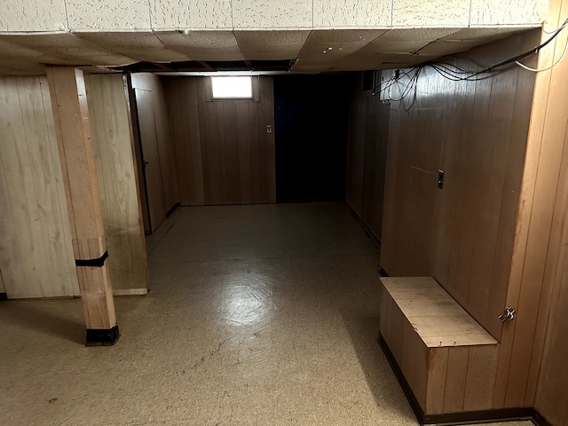 basement with a drop ceiling and wood walls