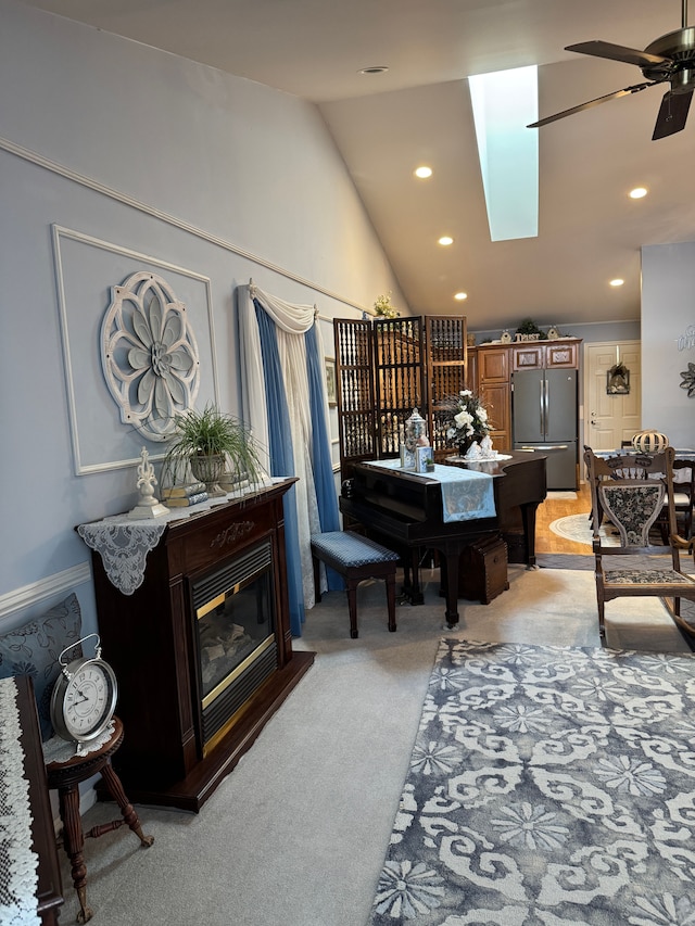 interior space with vaulted ceiling with skylight, light carpet, and ceiling fan