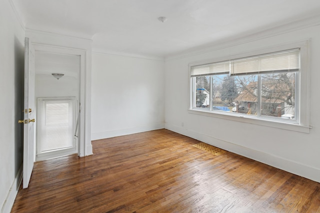 empty room with wood-type flooring and ornamental molding