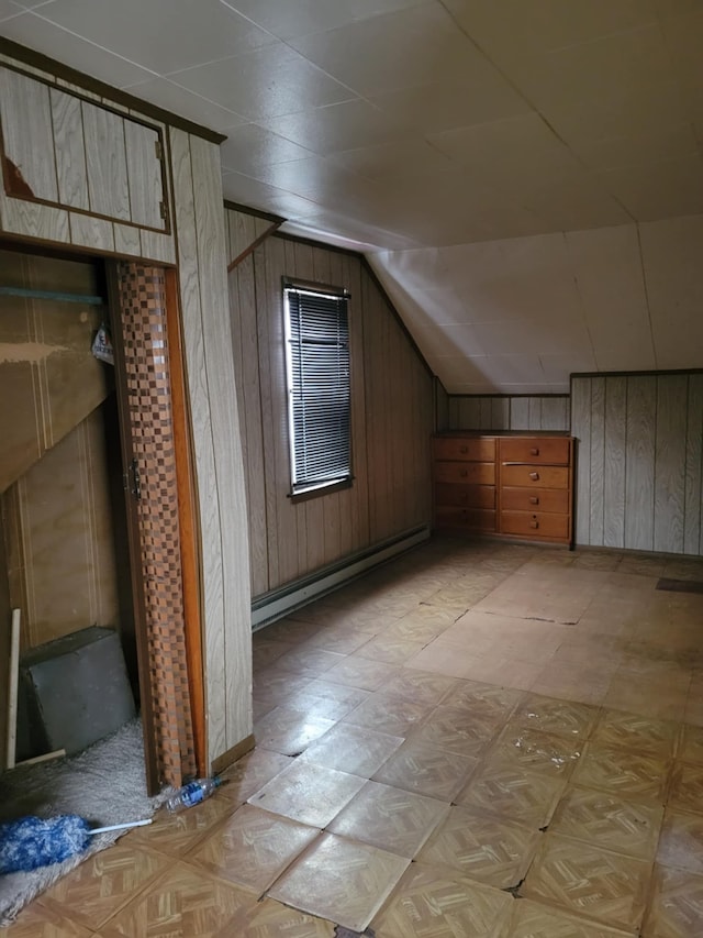 additional living space featuring a baseboard radiator, lofted ceiling, and wood walls