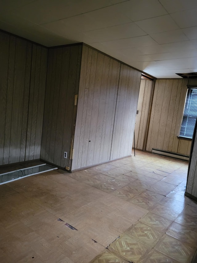 spare room with wood walls and a baseboard heating unit