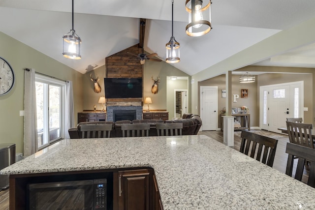 kitchen with light stone counters, hanging light fixtures, and a kitchen breakfast bar