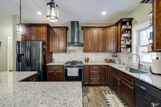 kitchen with sink, stainless steel appliances, light stone counters, decorative light fixtures, and wall chimney exhaust hood