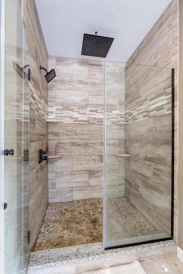 bathroom featuring a textured ceiling and a shower with shower door