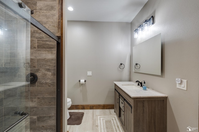 bathroom featuring vanity, hardwood / wood-style floors, a shower with door, and toilet