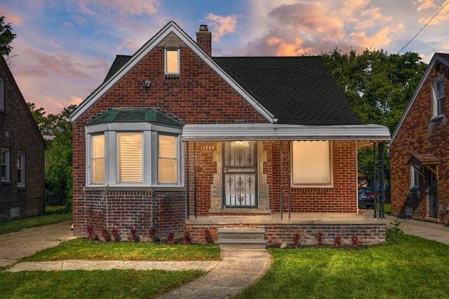 bungalow-style home with covered porch and a lawn