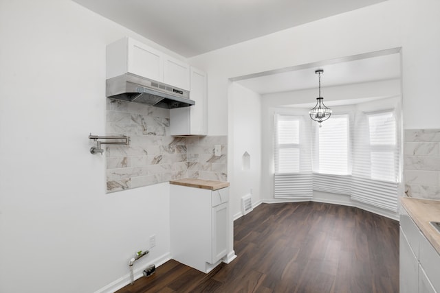 kitchen with dark wood-type flooring, wood counters, white cabinetry, pendant lighting, and decorative backsplash